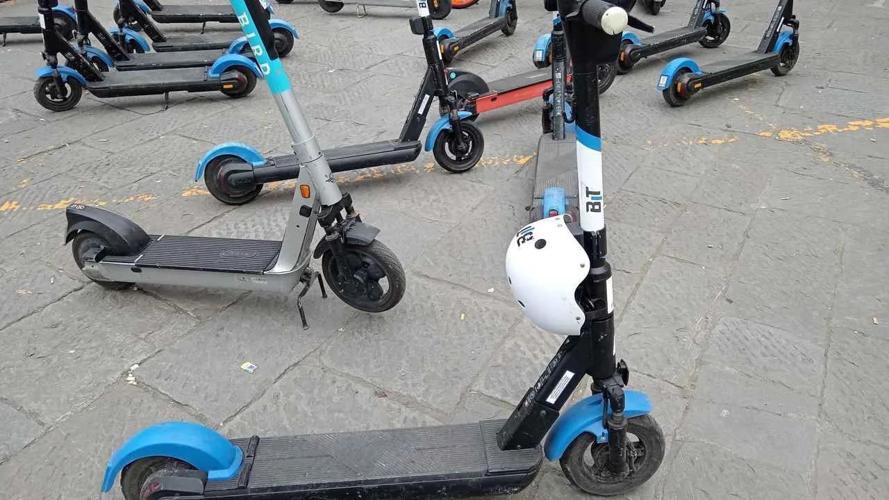 Shared electric kick-scooters parked upright in a paved public square; no people visible.