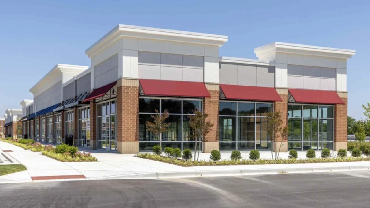 Newly built empty strip mall with red awnings under a clear blue sky