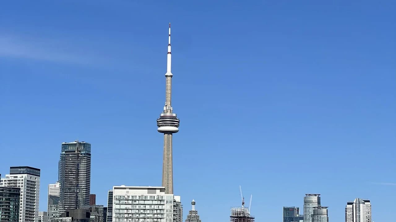 The Toronto skyline with the CN Tower under a clear blue sky; no people visible.