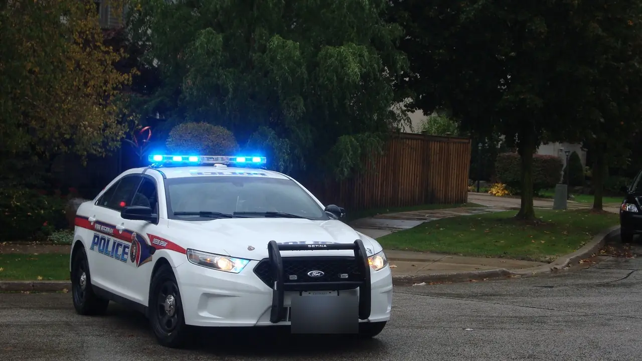 A marked Ontario police cruiser parked at a curb with its blue light bar flashing on a residential street; no people visible.