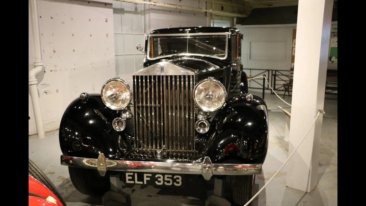 A classic black vintage car with a large chrome grille on display inside the Canadian Automotive Museum in Oshawa; no people present.